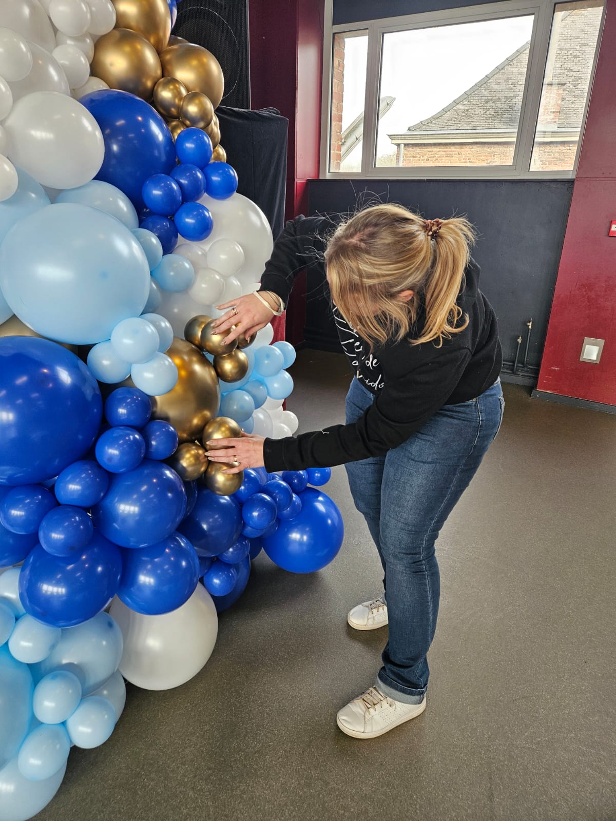 Sophie à l'œuvre sur une installation de ballons bleu et or